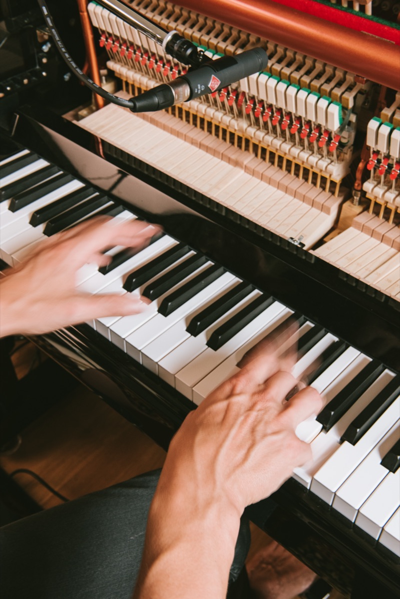 Hands moving quickly across piano keys, seen from above