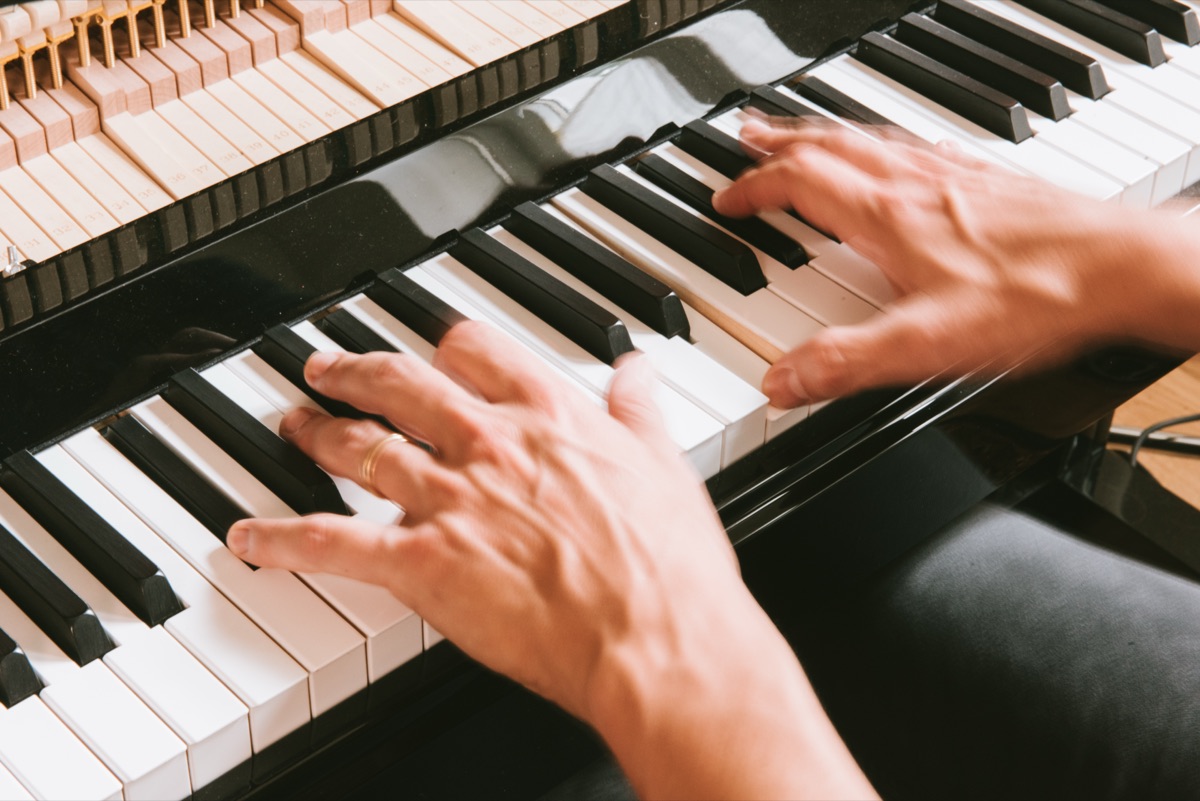 Hands playing piano keys, seen from above
