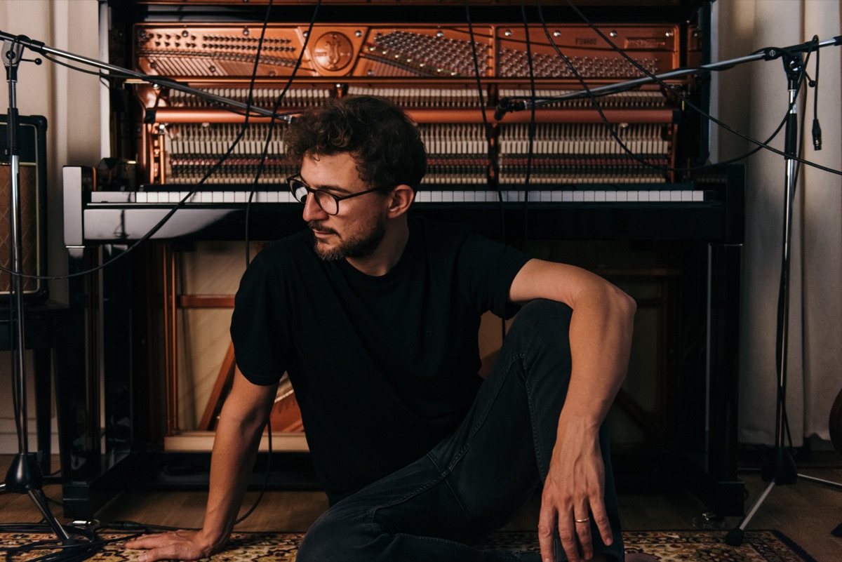 Claudio Donzelli sitting in front of an open upright piano, looking to the side