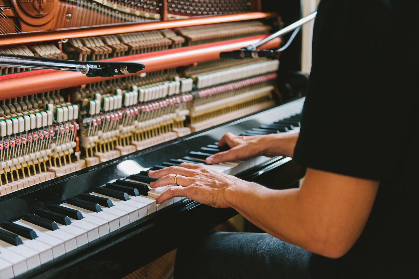 Hands playing an open upright piano